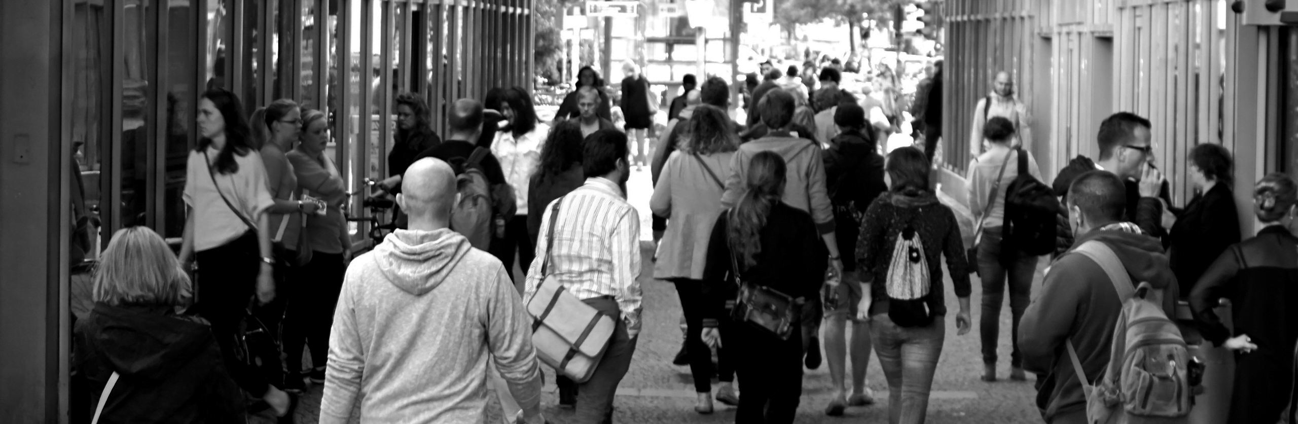 Human trafficking victims can be anywhere. Black and white photo of people walking away in a mall.
