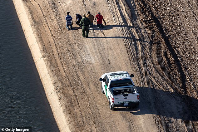 A U.S. Border Patrol agent detains immigrants who had crossed the border from Mexico near the All-American Canal on September 28, 2022 near Yuma, Arizona