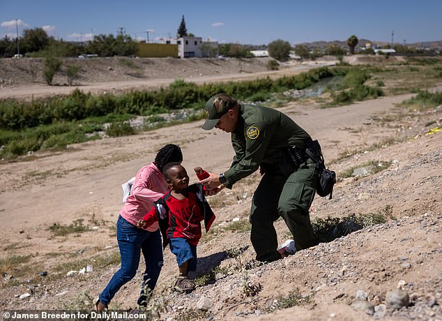 A Haitian family crosses the Rio Grande river from Ciudad Juarez in Mexico to El Paso, in the U.S., assisted by an official from Customs and Border Protection