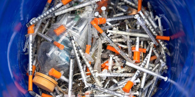 Heroin syringes fill a bucket after volunteers collected them at a homeless encampment in Seattle, Washington, on March 1, 2022.
