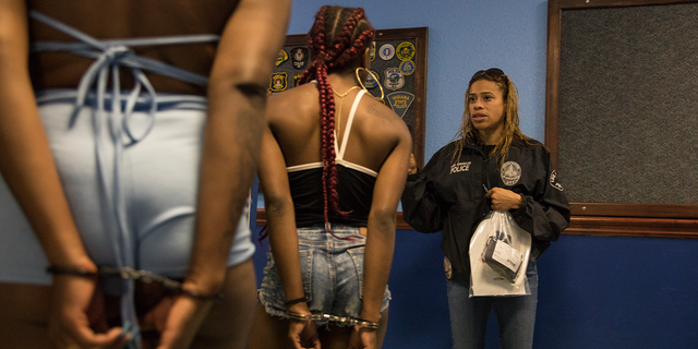 An officer of the Los Angeles Police Department's vice squad, right, speaks to two recently arrested women in the 77th Division police headquarters in Los Angeles.